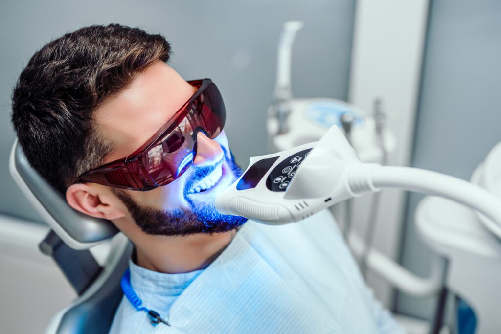 How Do I Choose Between Teeth Whitening Options? - Viera Dental Arts | Dentist in Melbourne FL - Dentist starting teeth whitening procedure with young man.