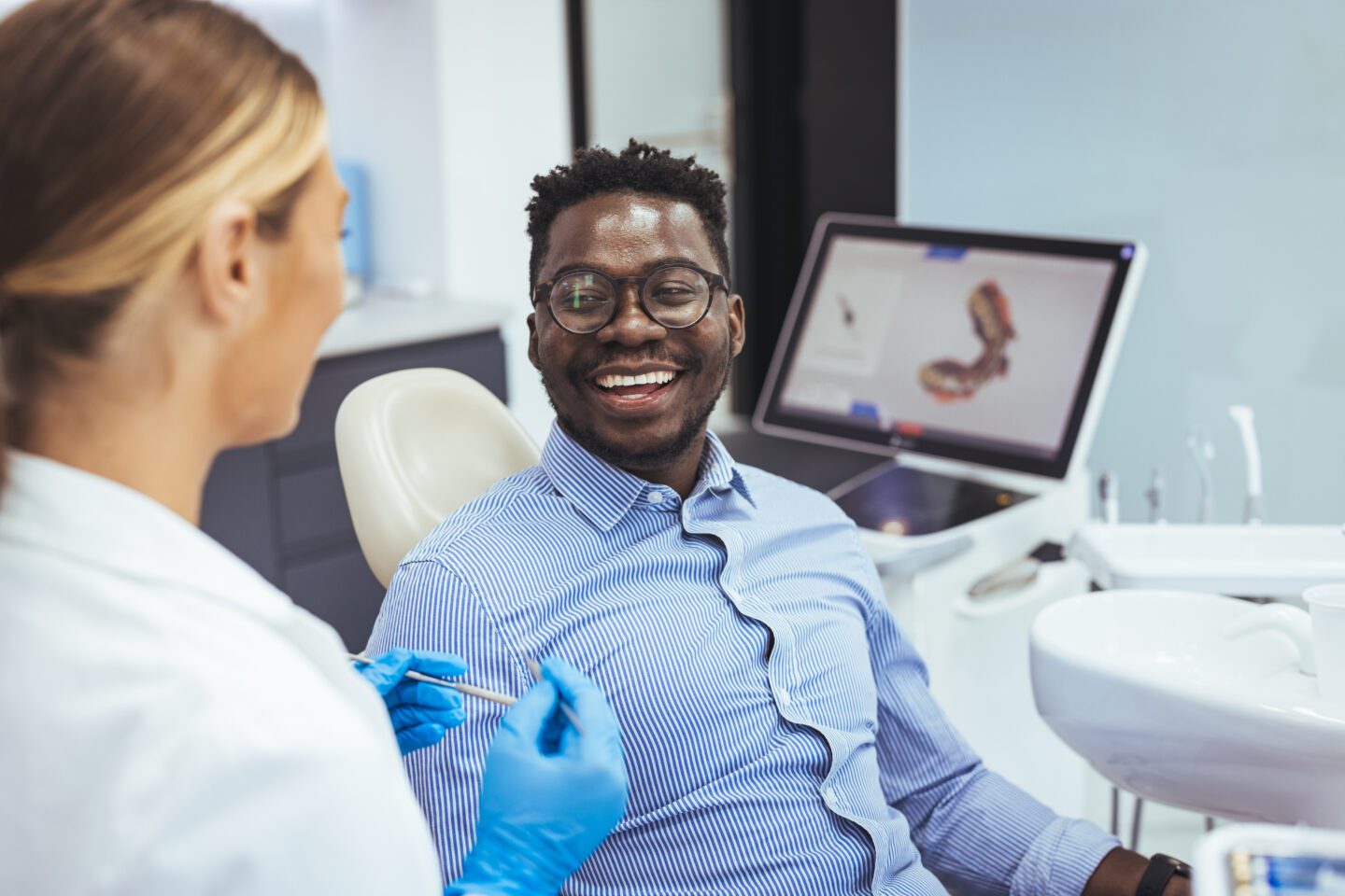 AdobeStock 523549017 scaled - Viera Dental Arts | Dentist in Melbourne FL Smiling african guy in dentist chair looking with trust at his doctor, close up. Young African American Man Getting Teeth Treatment With Professional Stomatologist At Modern Clinic, Closeup