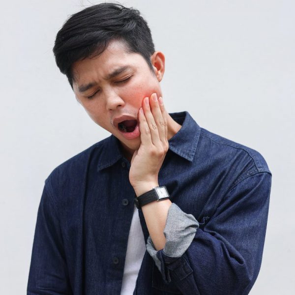 close up young asian man frown and use hand to massage on cheek after feeling pain or hurt from tmj muscle symptom at home for un healthy lifestyle and treatment concept