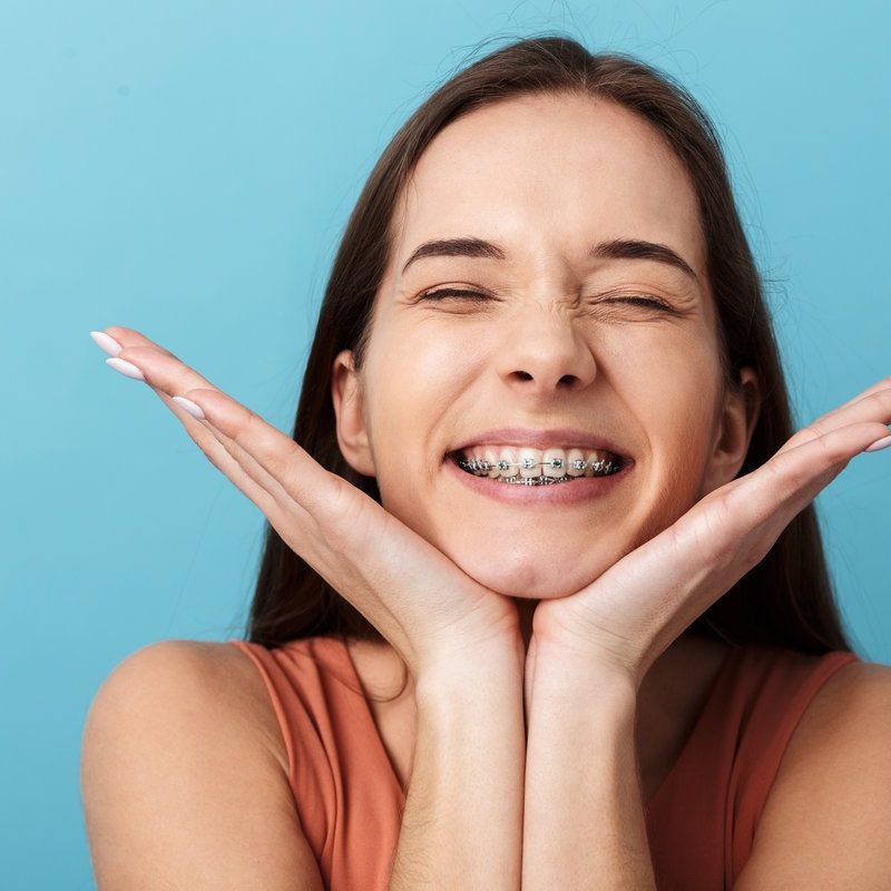 Close up of a cute lovely young girl standing isolated over blue background, grimacing