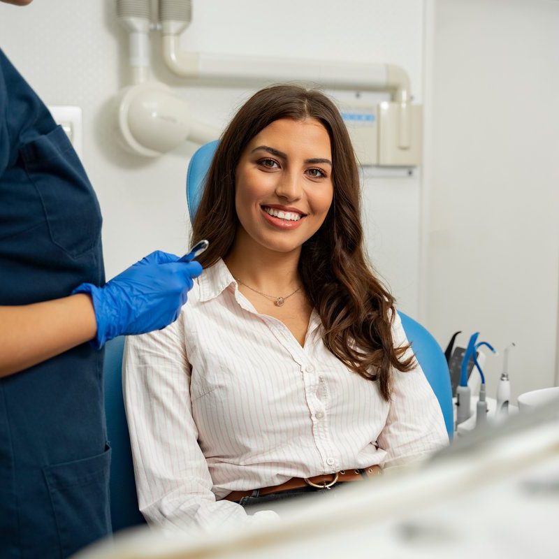Satisfied patient sitting in dentist chair. Gorgeous young woman in dental clinic smiling from a chair next to dentist