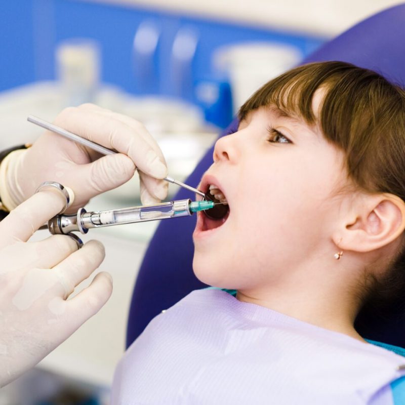 dentist holding a syringe and anesthetizing his patient