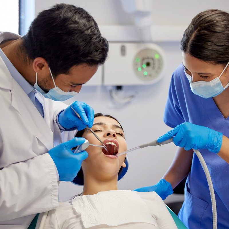 Dentist, team and oral care with patient for healthcare, wellness and teeth whitening in practice. Woman, dental professional and PPE with tools for consultation, cleaning and filling on chair.